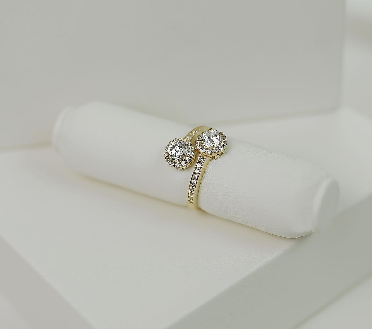 yellow gold twin-halo bypass ring on a white leather display roll
