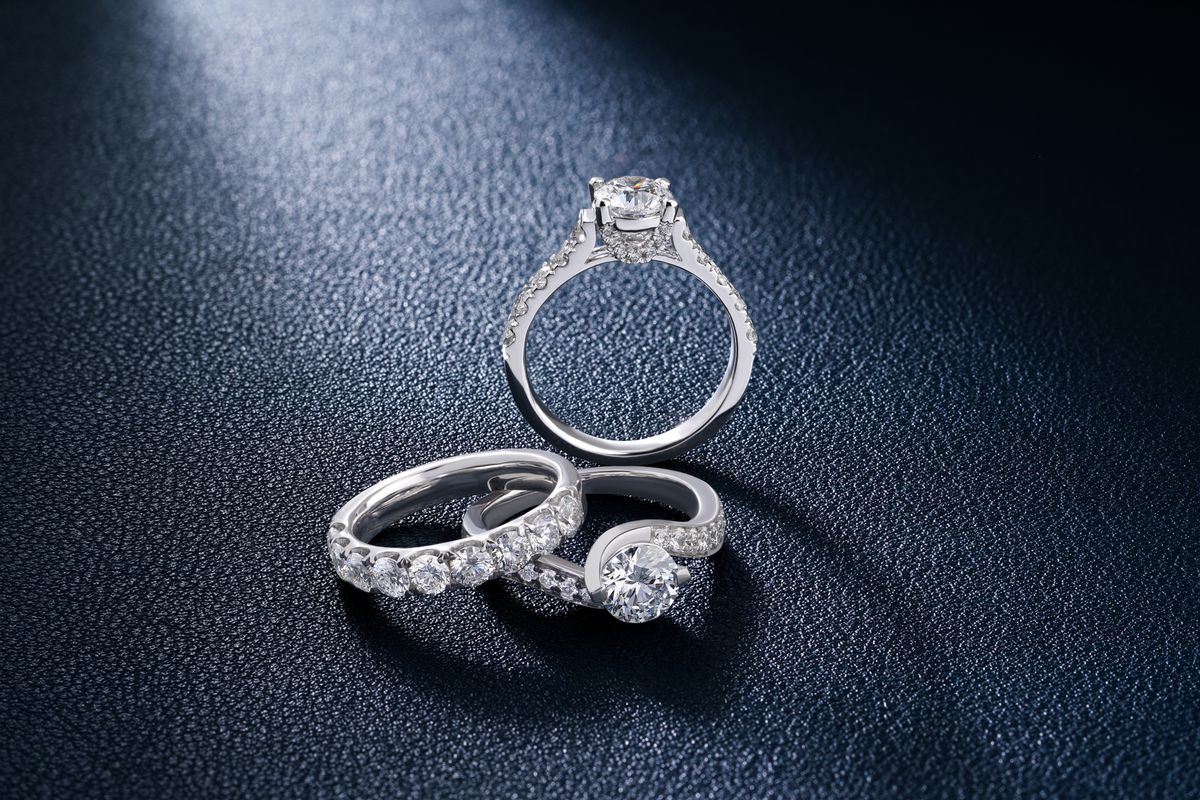 three white metal diamond rings on dark textured leather