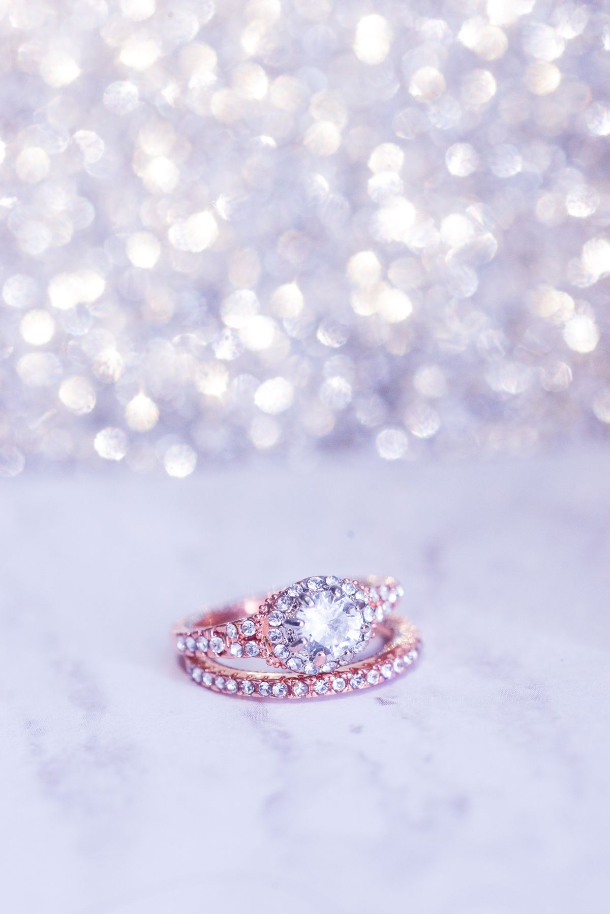 rose gold engagement ring staged on a bright textured surface