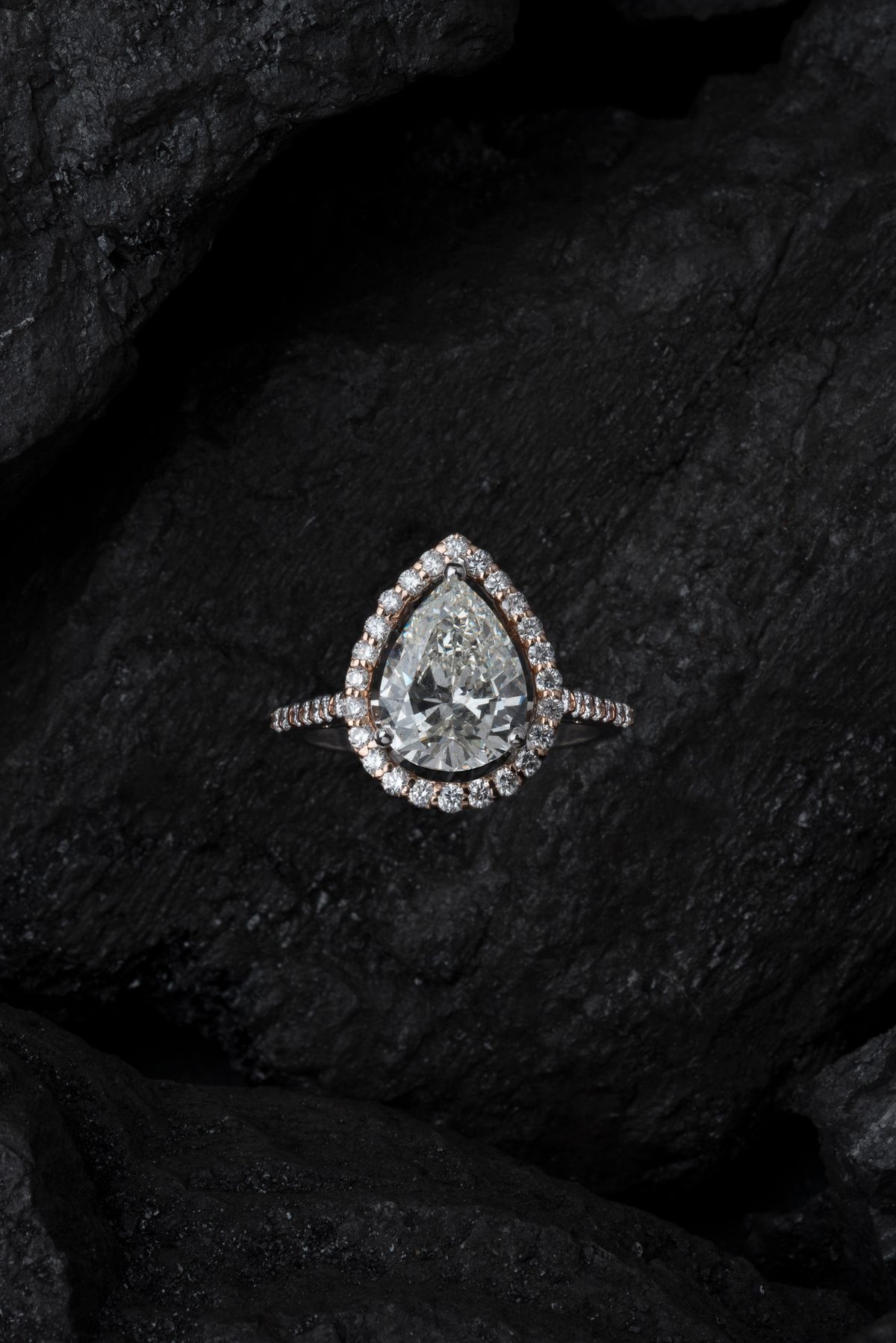 macro render of a pear cut diamond halo ring on dark stone