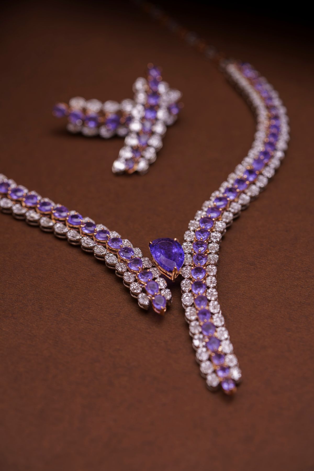 amethyst and diamond necklace with matching earrings laid on a brown backdrop
