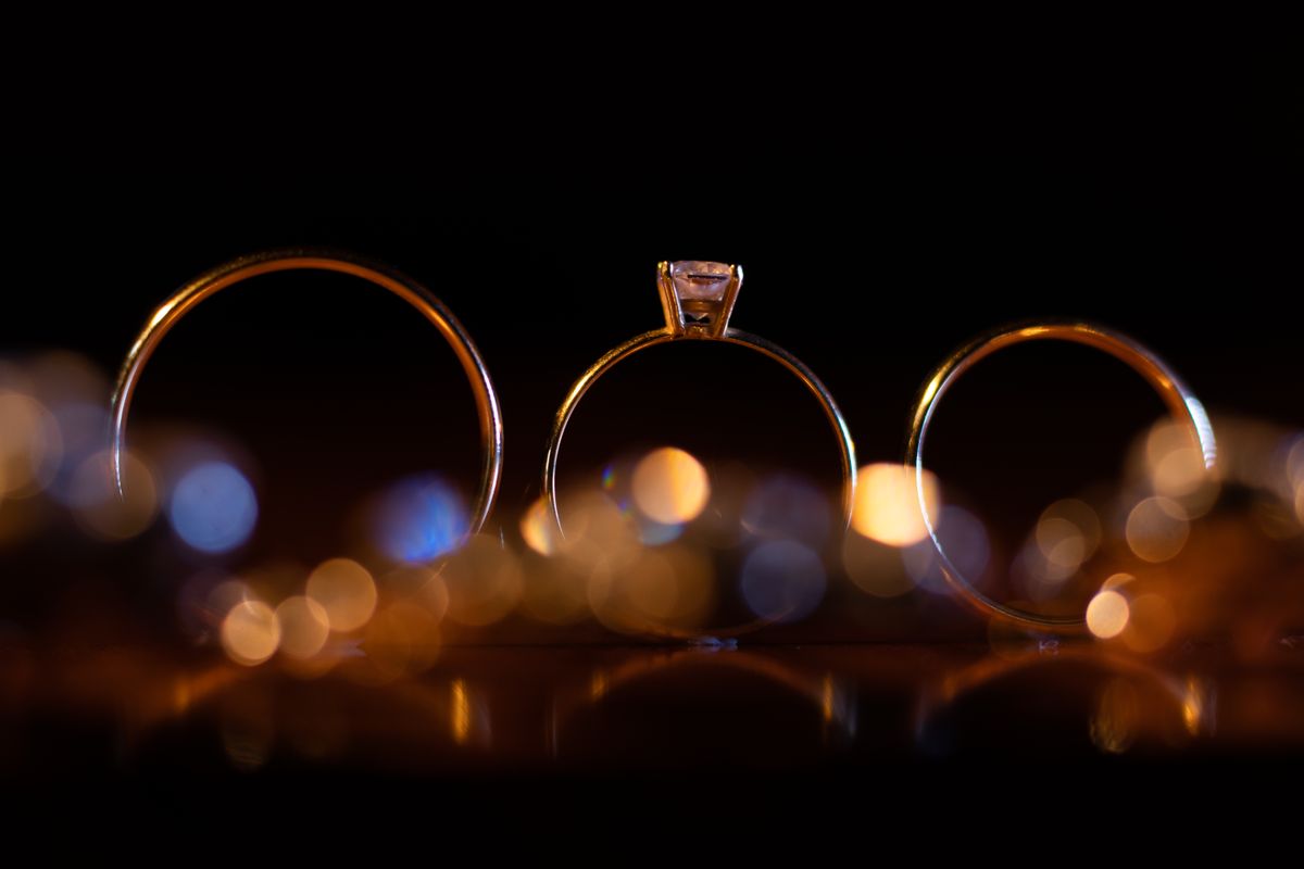 three gold rings backlit against a dark background with bokeh highlights behind them